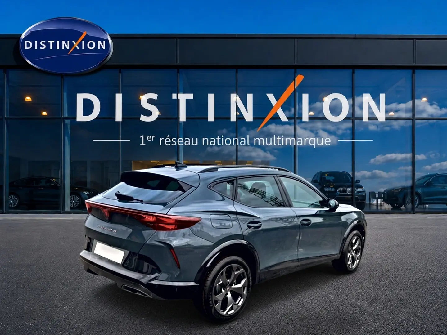 Vue 3/4 arrière droite du CUPRA Formentor 1.5 etsi hybrid bleu fjord avec jantes 18 pouces devant un showroom Distinxion.