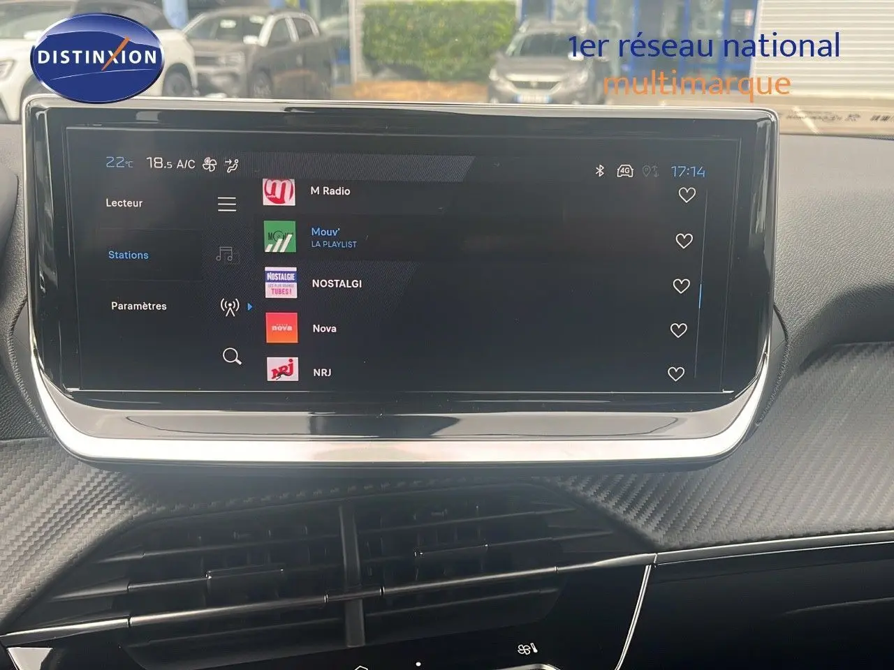 Écran tactile central du tableau de bord du Peugeot 2008 blanc Okenite, affichant les stations radio en extérieur.