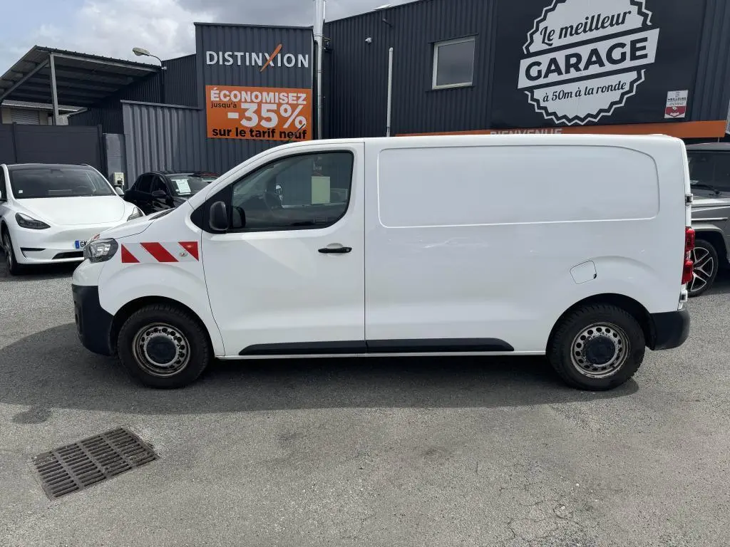 Profil droit d'un utilitaire blanc Peugeot Expert Fourgon 2018 avec bandes rouges diagonales sur l'aile avant.