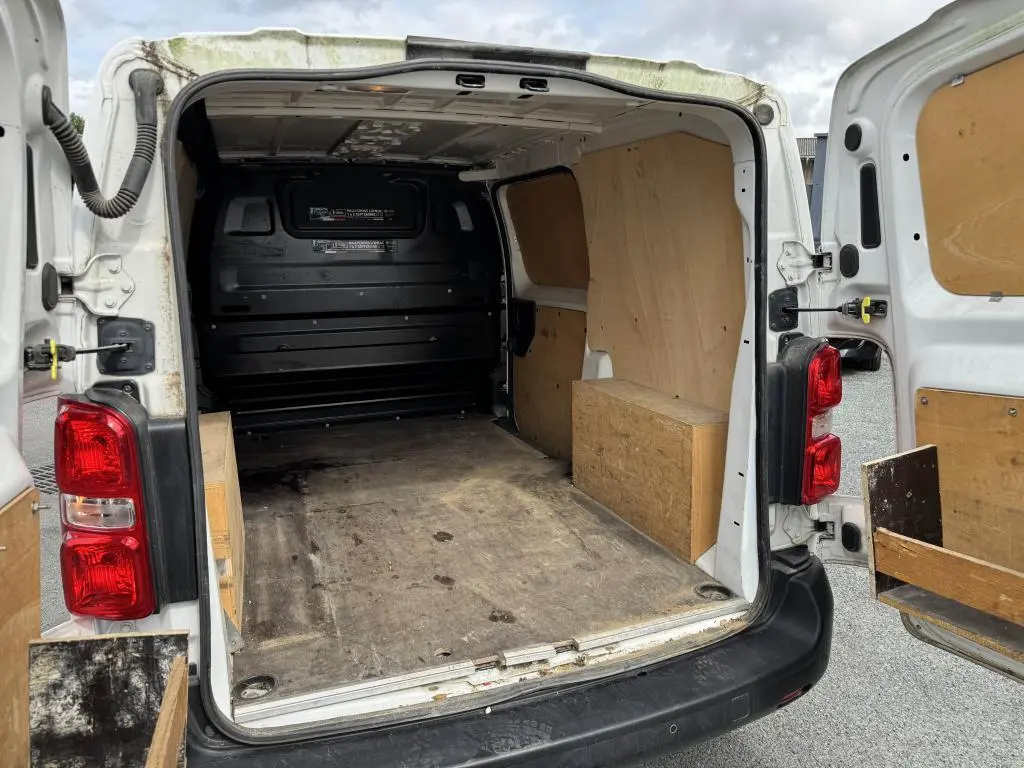 Vue arrière ouverte du Peugeot Expert Fourgon blanc avec intérieur de chargement en bois et plancher usé visible.