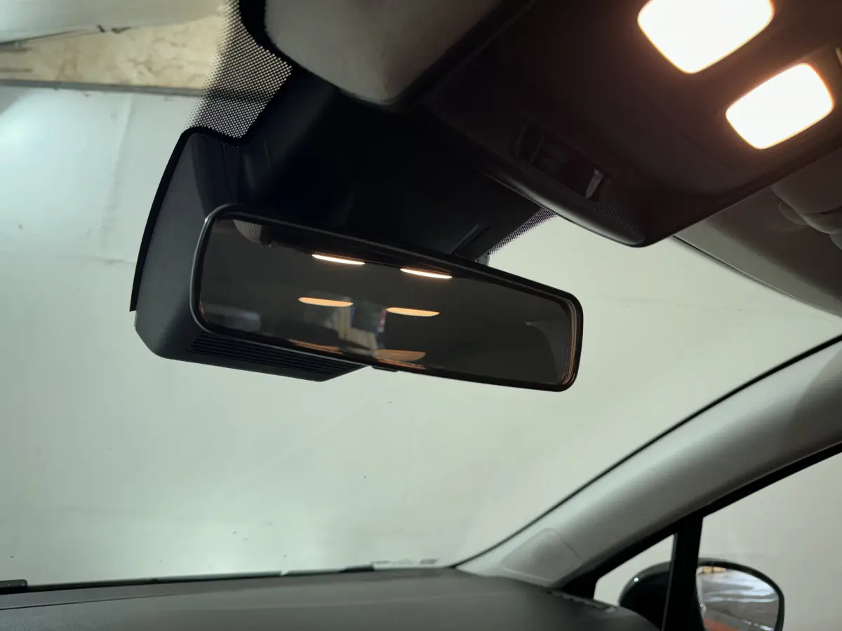 Gros plan sur le rétroviseur intérieur et le plafond clair d'une Renault Clio gris clair, vue depuis l'habitacle avant droit.