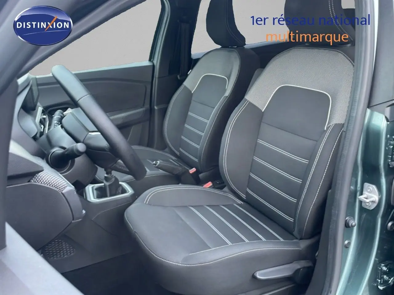 Vue intérieure centrée sur la console centrale du Dacia Jogger 2025, montrant la boîte manuelle et les sièges en tissu noir.