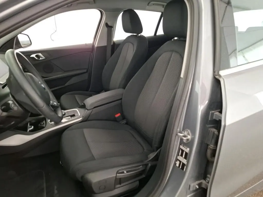 Intérieur de la BMW Série 1 116d 2022 en gris, vue côté conducteur avec sièges tissu noirs et console centrale.
