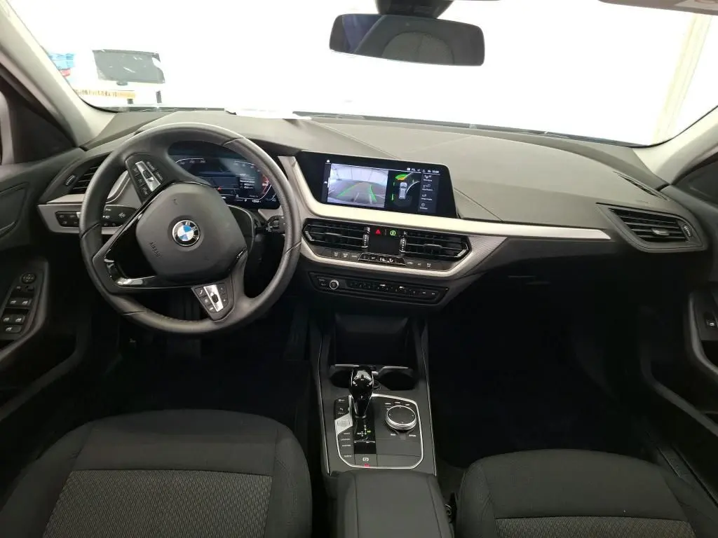 Vue intérieure du poste de conduite de la BMW Série 1 116d 2022 avec tableau de bord numérique et écran central tactile.