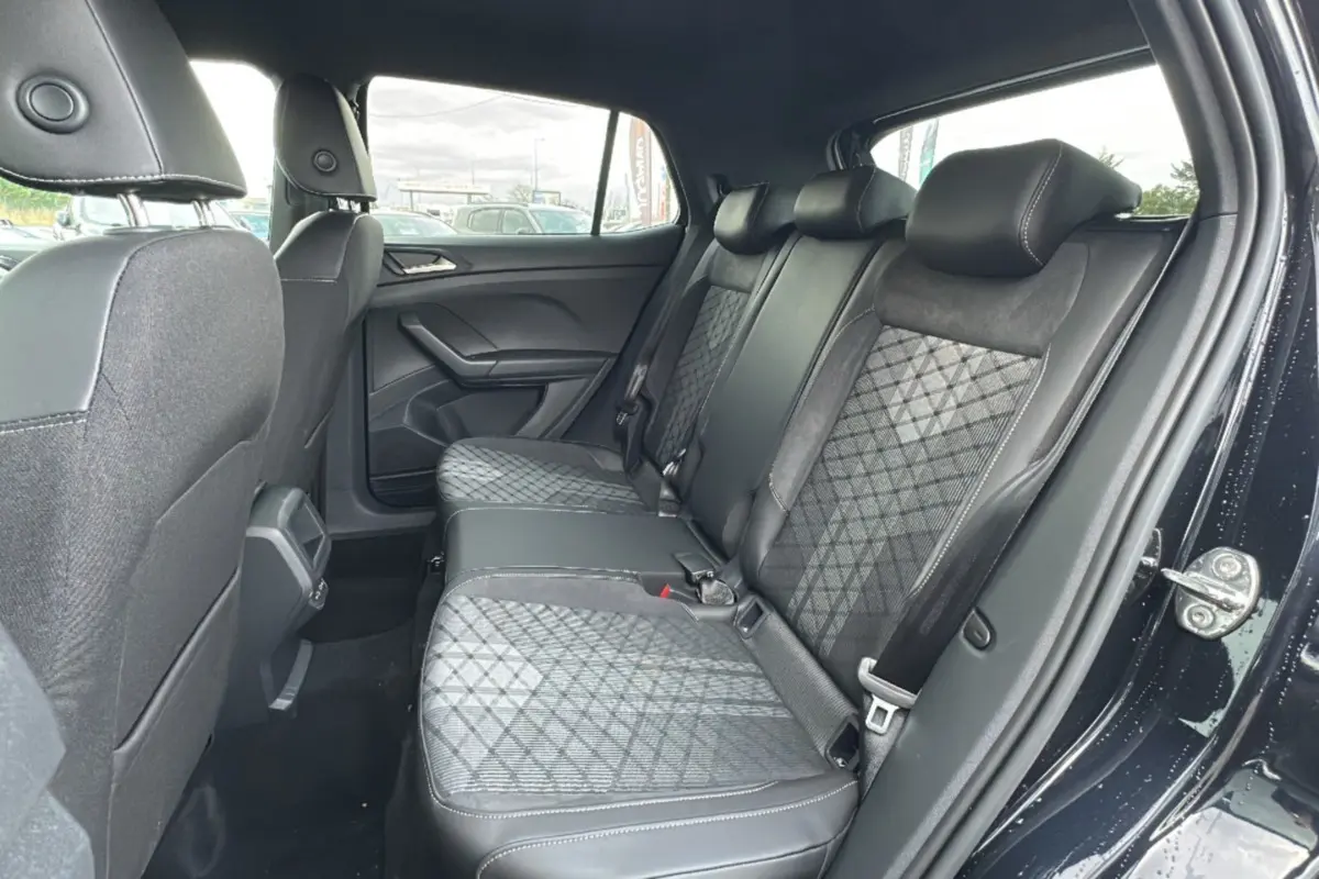 Vue intérieure côté droit montrant la banquette arrière en tissu noir avec motifs géométriques du Volkswagen T-Cross noir intense 2025.