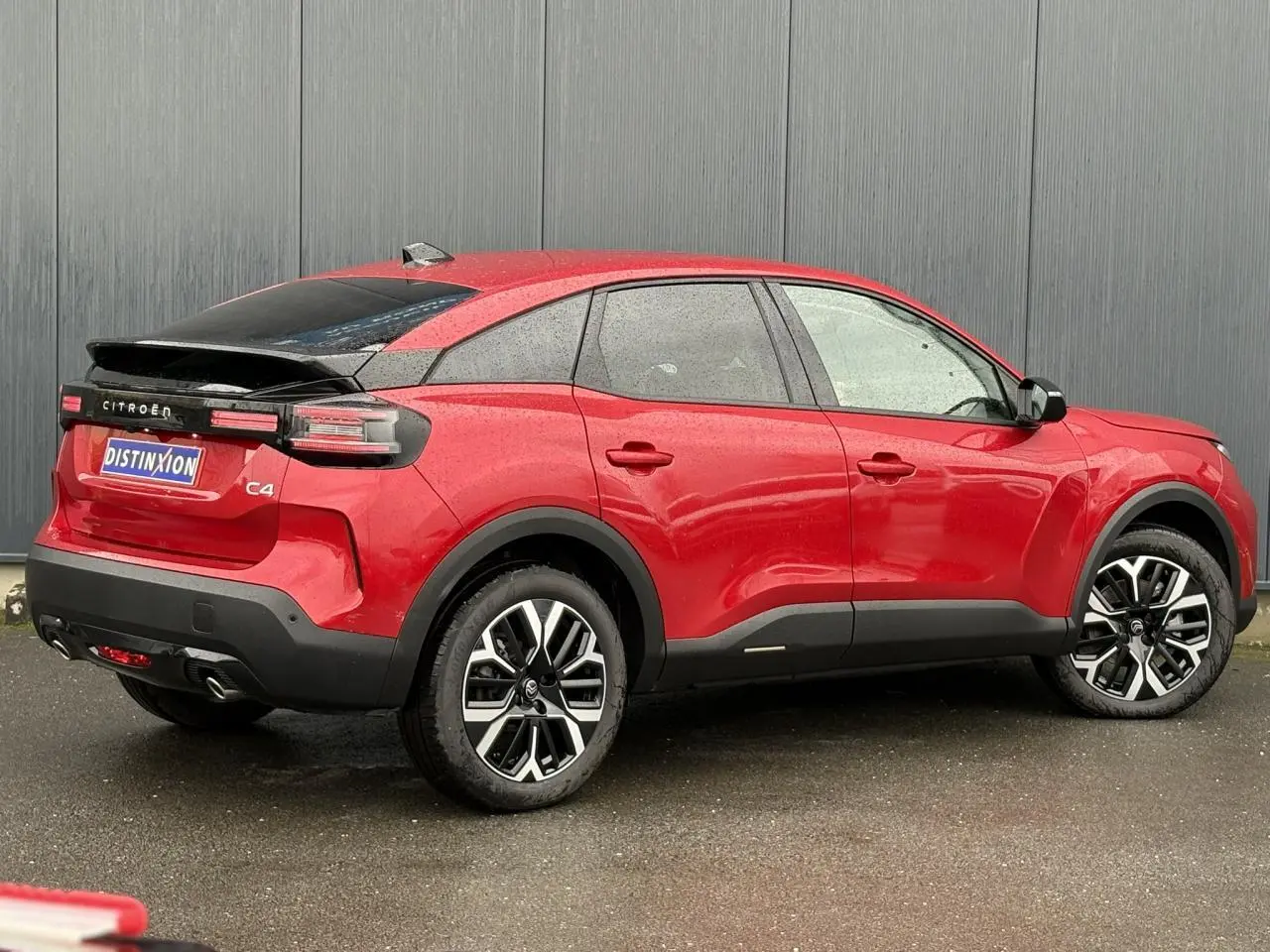 Vue 3/4 arrière droite d'une Citroën C4 rouge Elixir avec toit noir et jantes alliage 18 pouces diamantées.