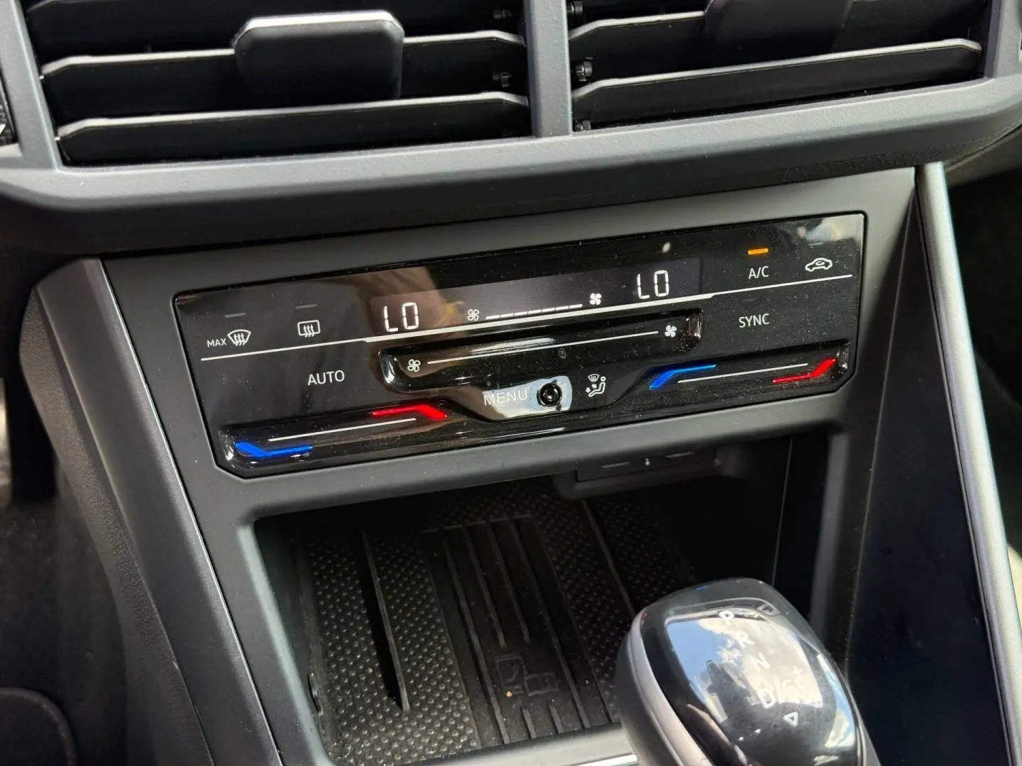 Gros plan sur la console centrale grise du Volkswagen Taigo 2025 avec commandes climatisation et levier de boîte automatique.
