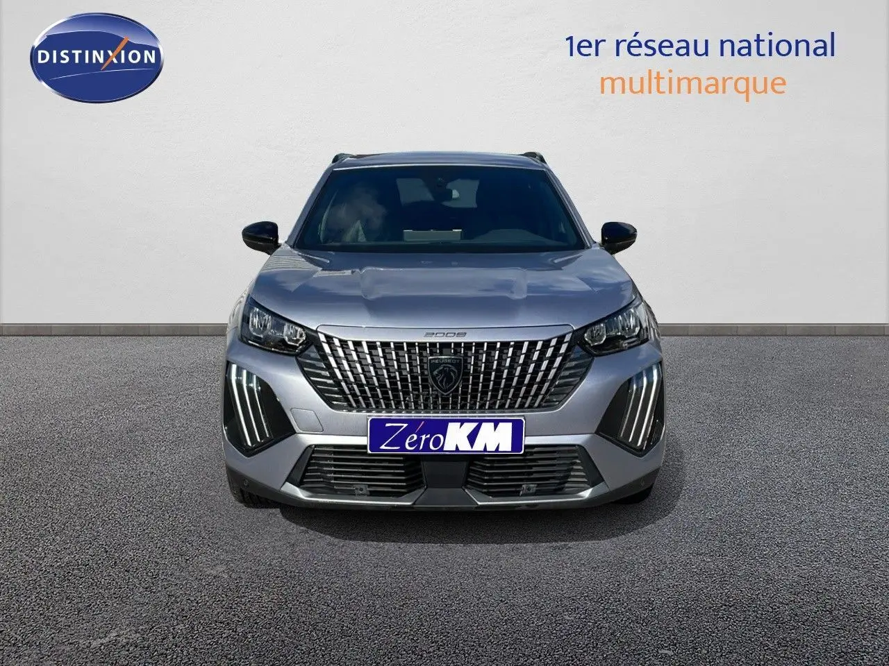 Peugeot 2008 gris Artense métal vue de face, avec calandre distinctive et feux LED verticaux allumés.