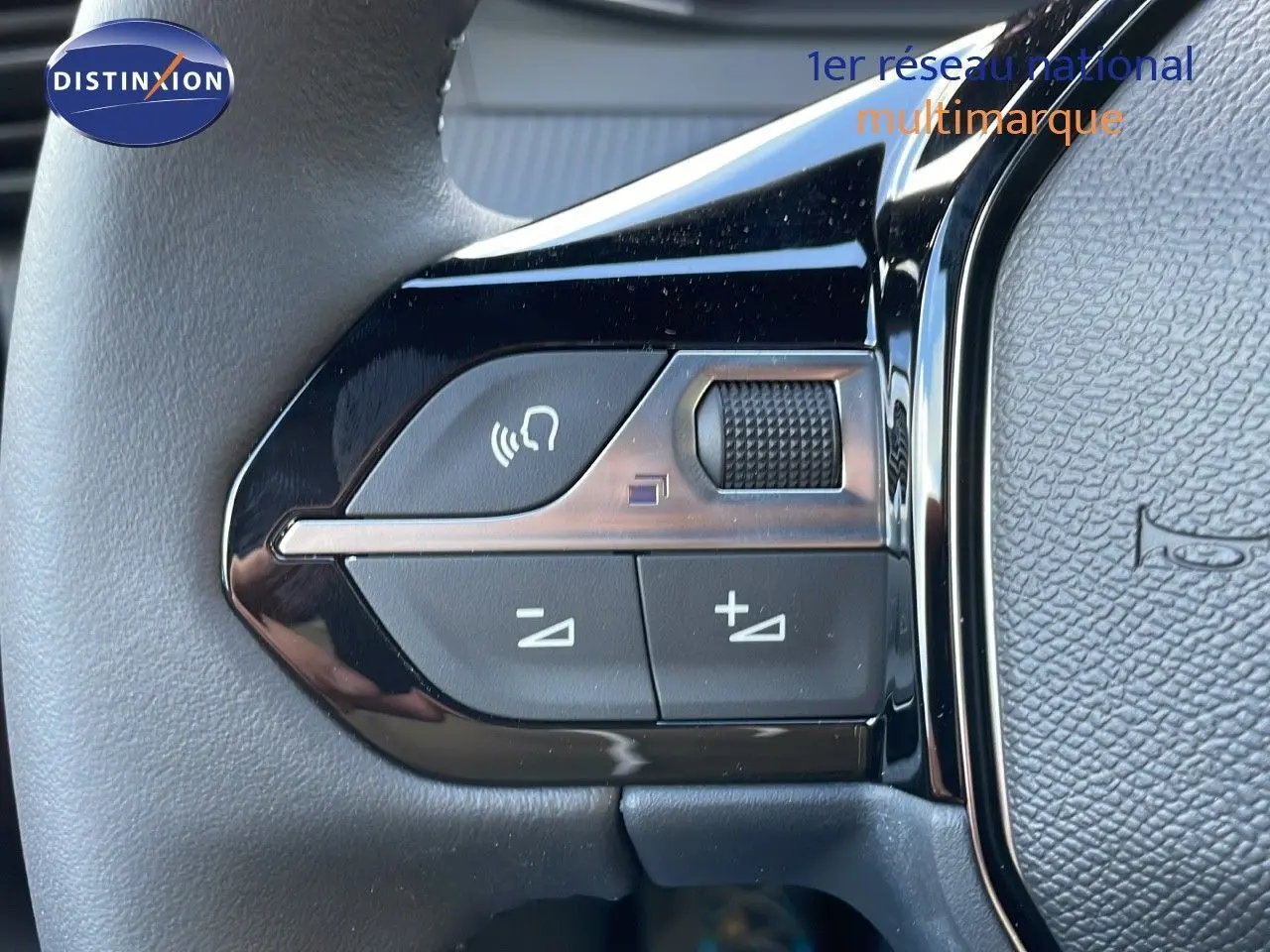 Gros plan sur les commandes de volume et appel au volant cuir noir du Peugeot 2008 gris Artense Metal.