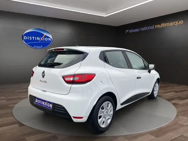 Vue 3/4 arrière droite d'une Renault Clio IV blanche de 2019 en version Société Diesel, sur fond showroom Distinxion.