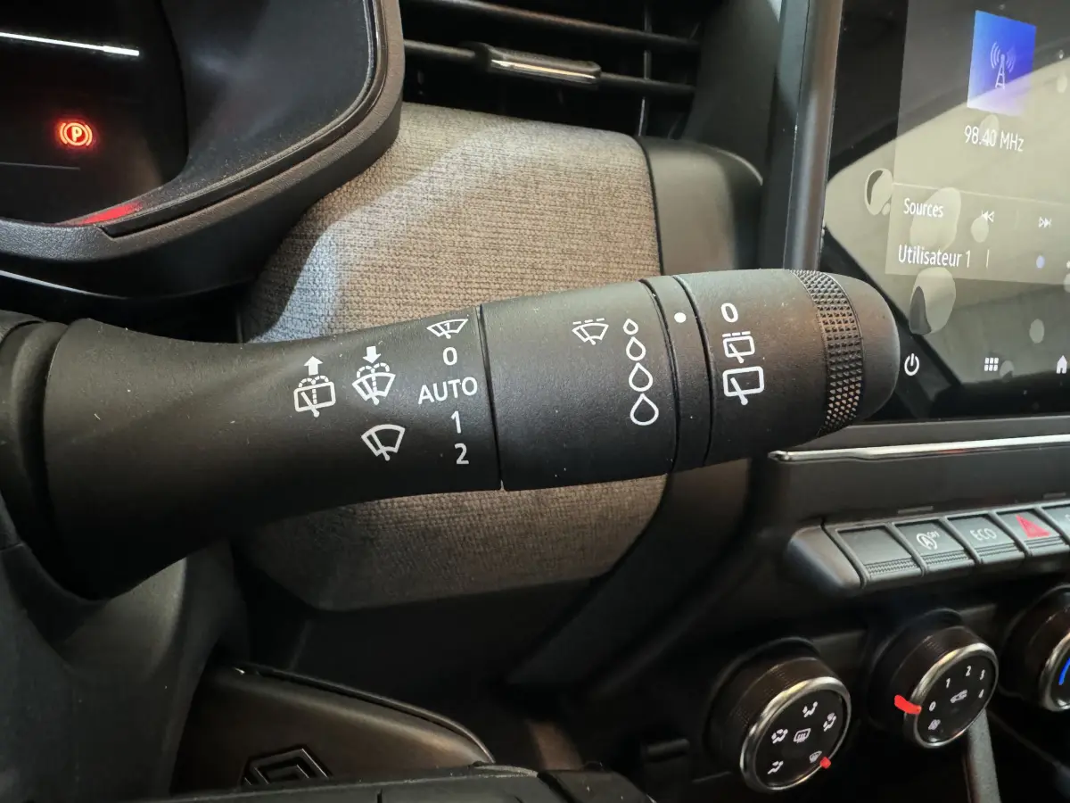 Gros plan sur la commande d'essuie-glace à gauche du volant dans l'habitacle gris clair d'une Renault Clio 2025.