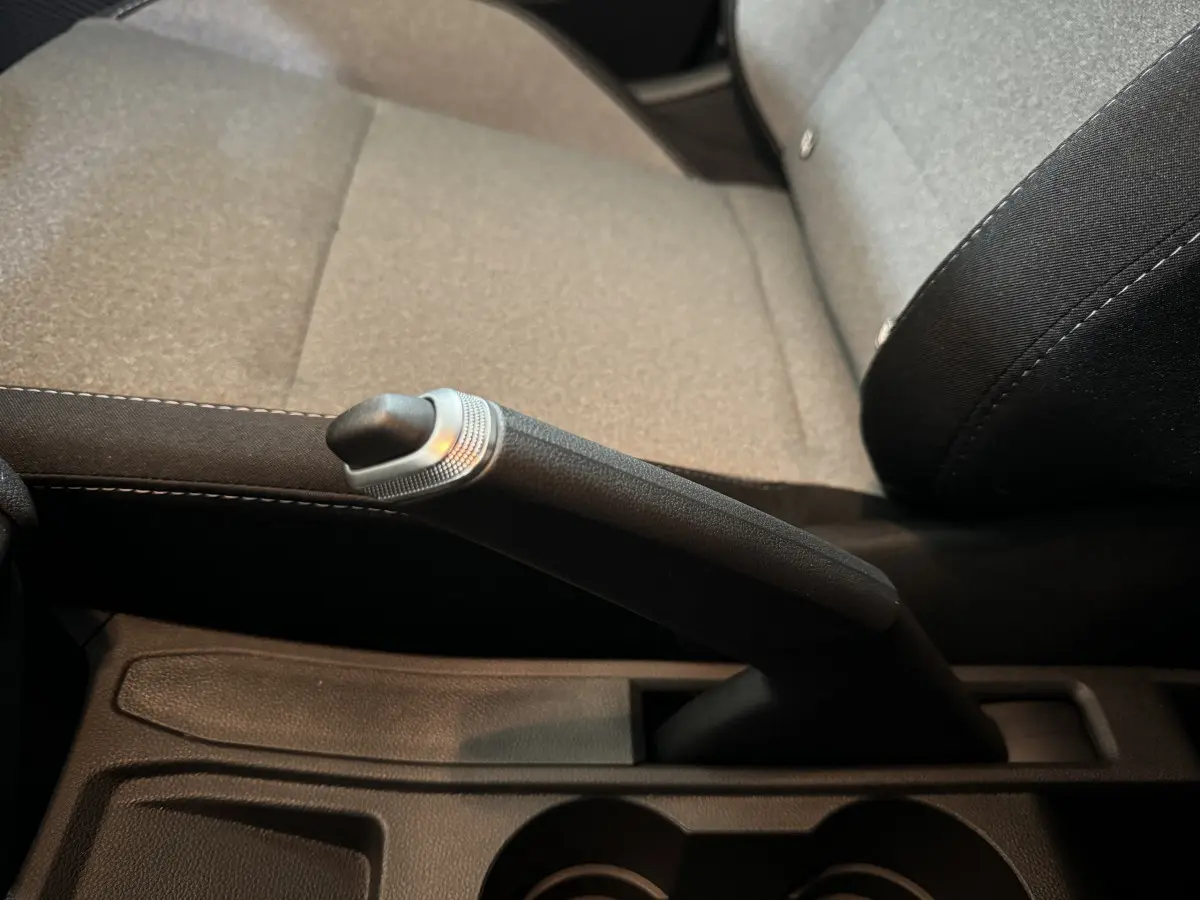 Le frein à main manuel en gros plan entre les sièges gris clair de la Renault Clio Evolution 2025.