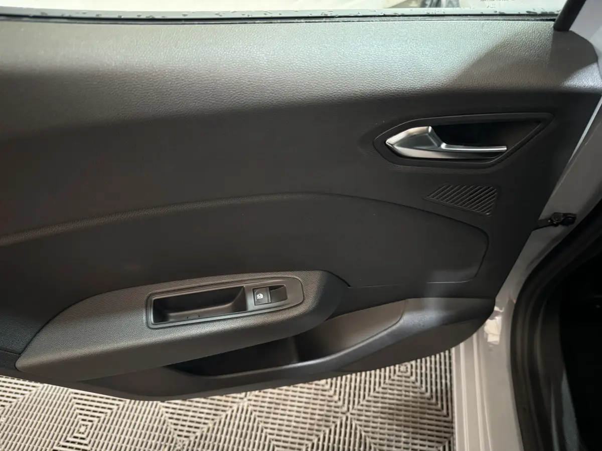 Vue intérieure de la porte avant droite gris clair de la Renault Clio Evolution Blue dCi 100 avec poignée et commande de vitre électrique.