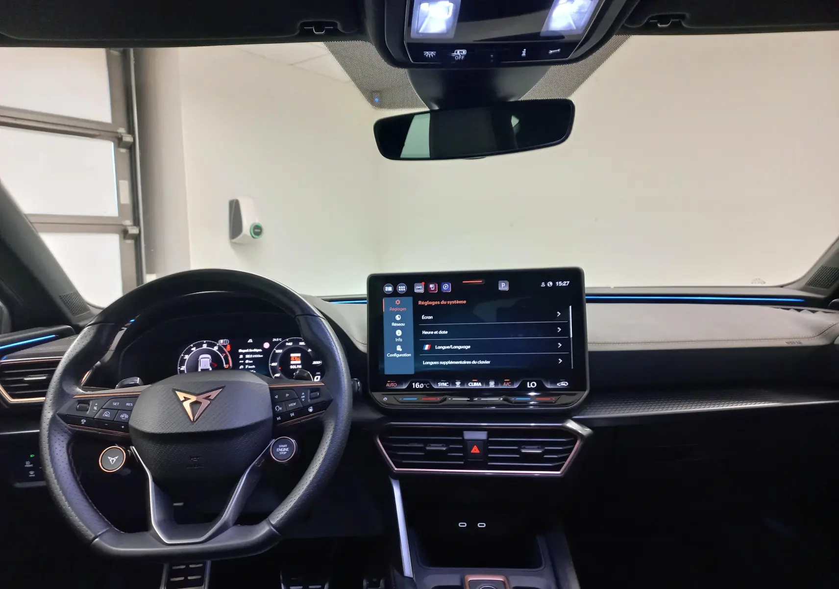 Vue intérieure du tableau de bord et volant CUPRA Leon Phase 2 avec écran tactile central et éclairage d'ambiance bleu.