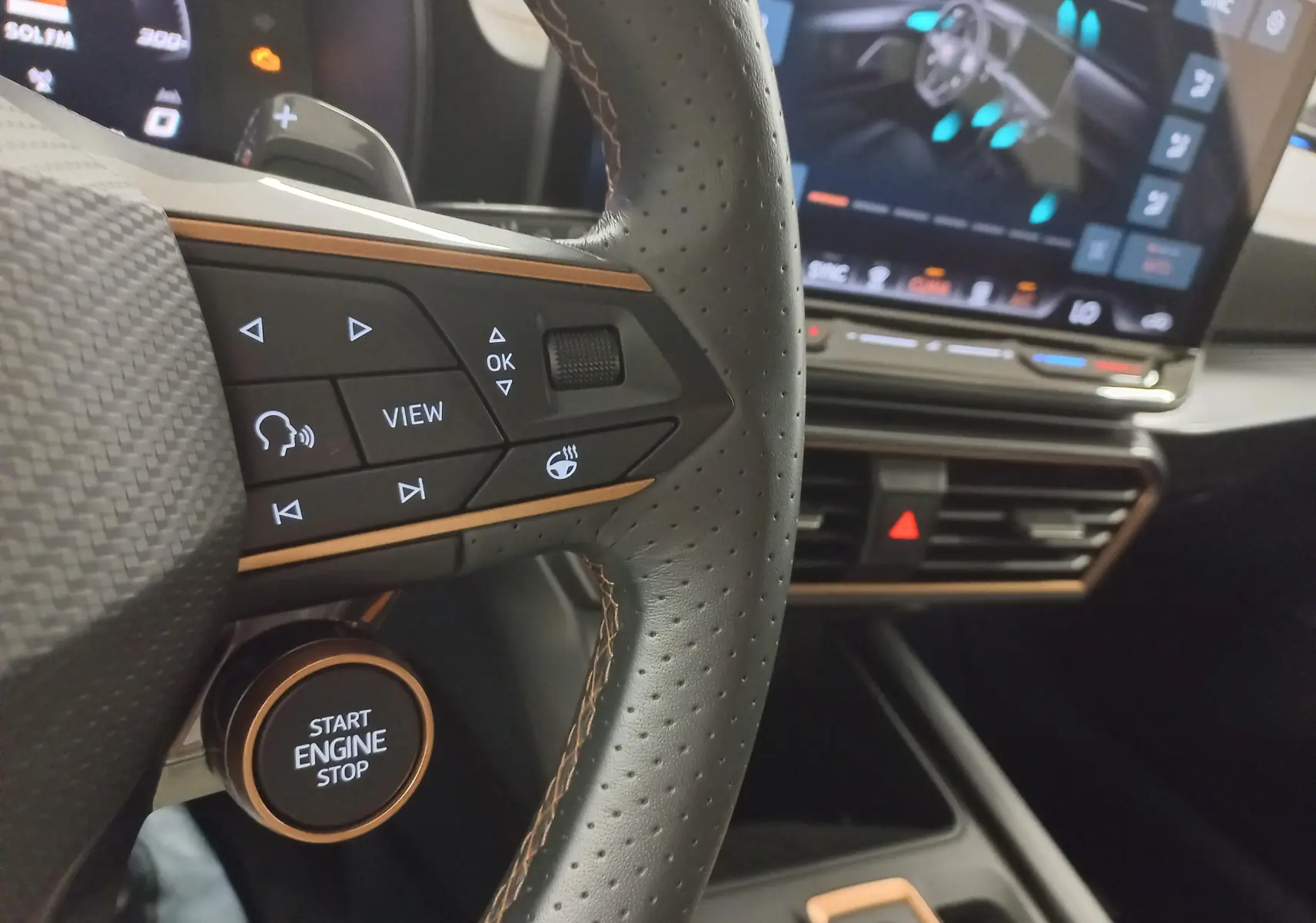 Gros plan sur le volant cuir perforé avec commandes multifonctions et bouton start/stop de la CUPRA Leon 2025.