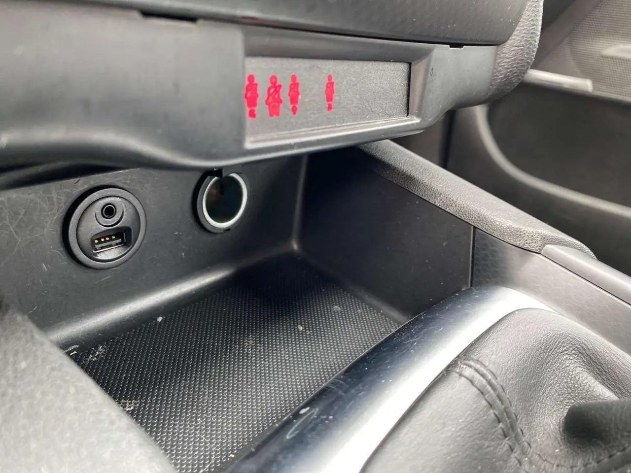 Prise USB et allume-cigare dans la console centrale d'une DS4 2016, avec indicateurs de ceinture allumés en rouge.