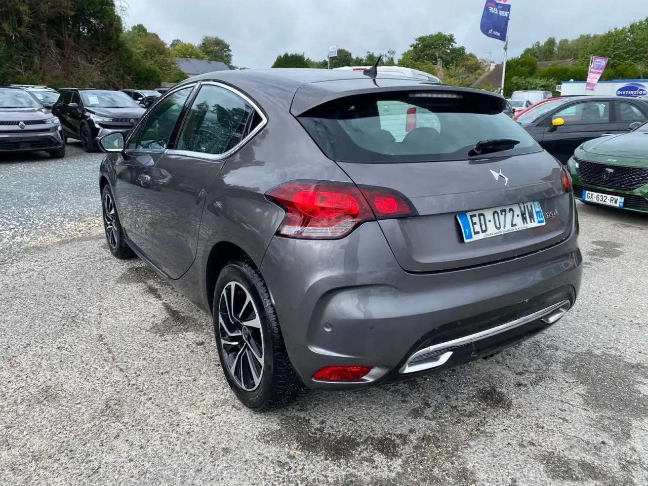 Vue 3/4 arrière droite d'une DS4 gris clair avec feux LED et jantes alliage au stationnement extérieur.