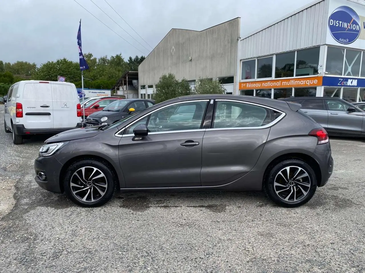 Profil côté gauche d'une DS4 gris clair 2016 avec jantes alliage et lignes fluides, stationnée en extérieur devant un bâtiment.