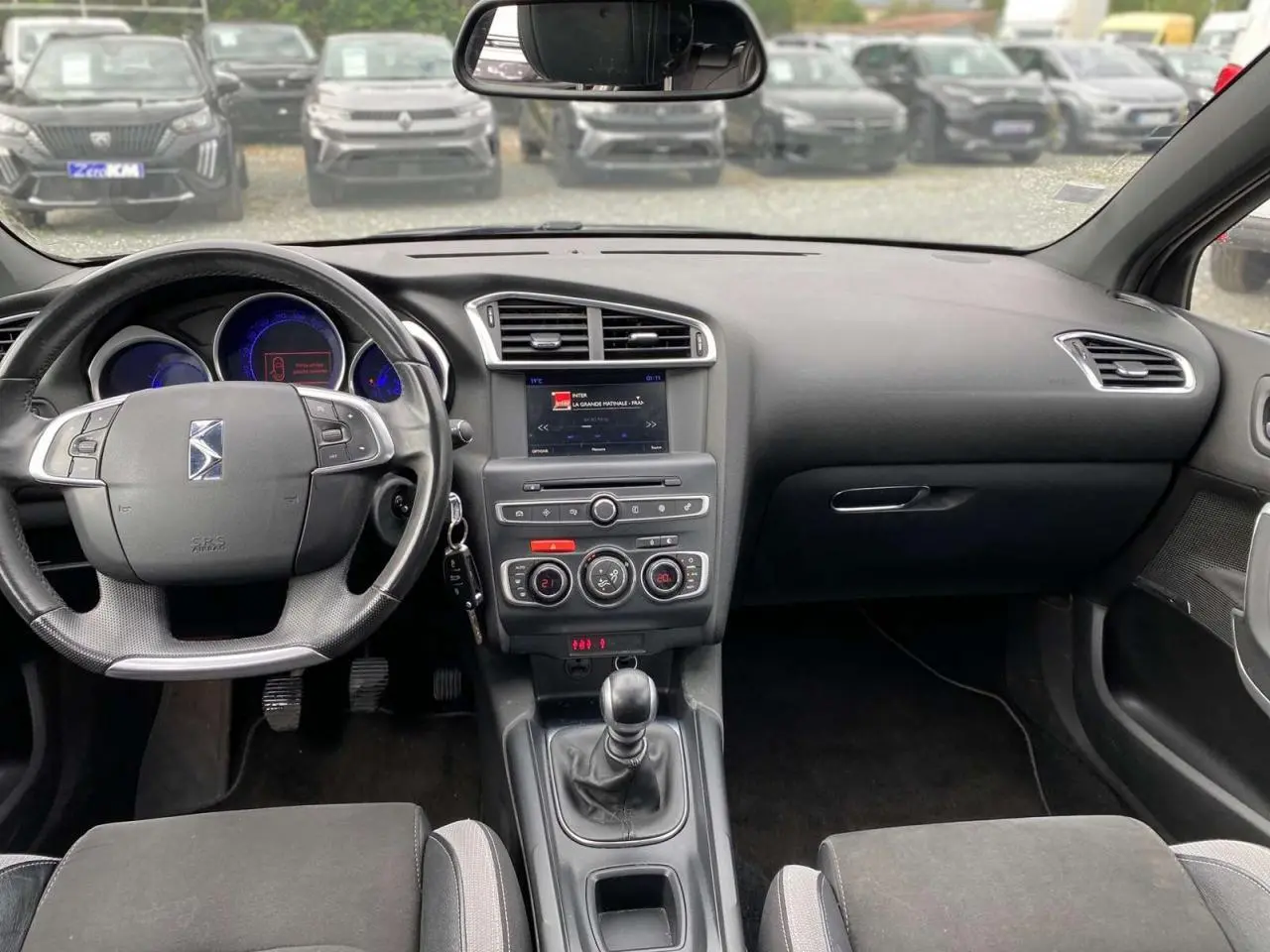 Tableau de bord et console centrale noirs d'une DS4 2016 avec volant multifonction et boîte manuelle visible.