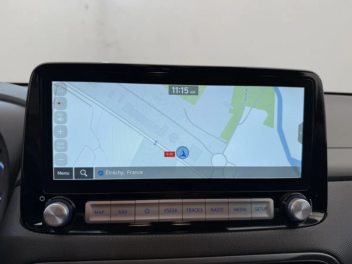 Écran tactile central affichant la navigation GPS dans un Hyundai Kona électrique gris clair, vue intérieure frontale.