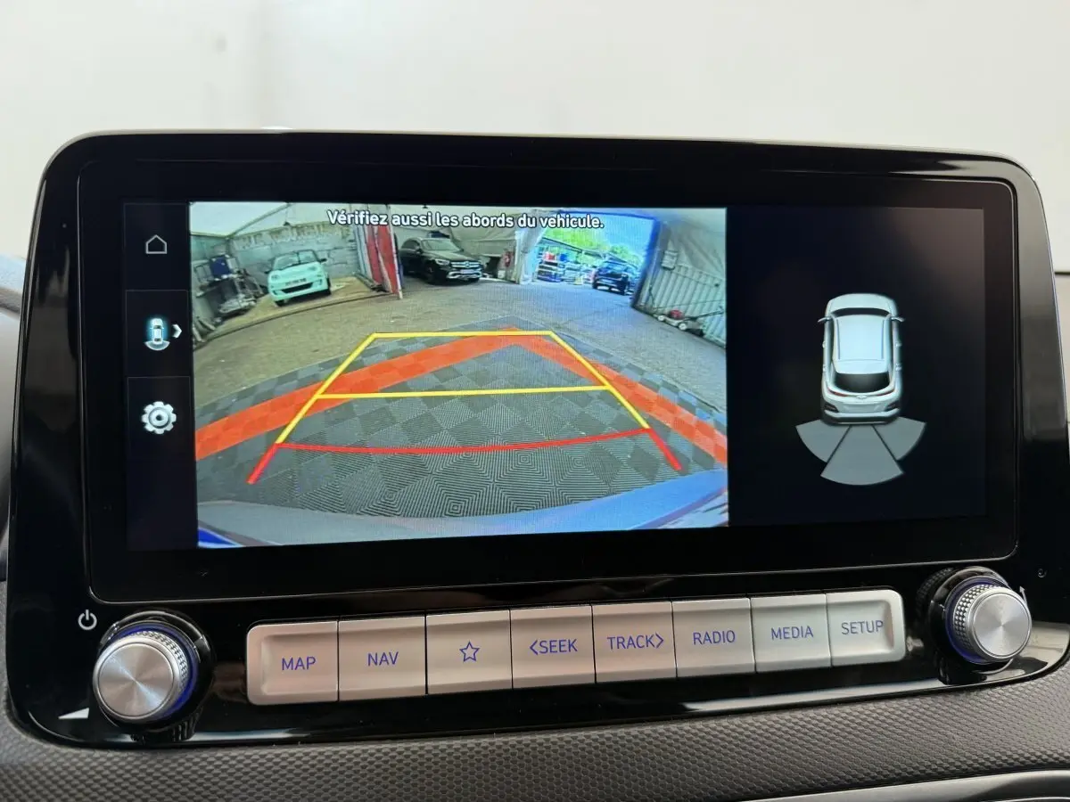 Écran tactile central du Hyundai Kona gris clair 2022 montrant la caméra de recul et l'aide au stationnement arrière.