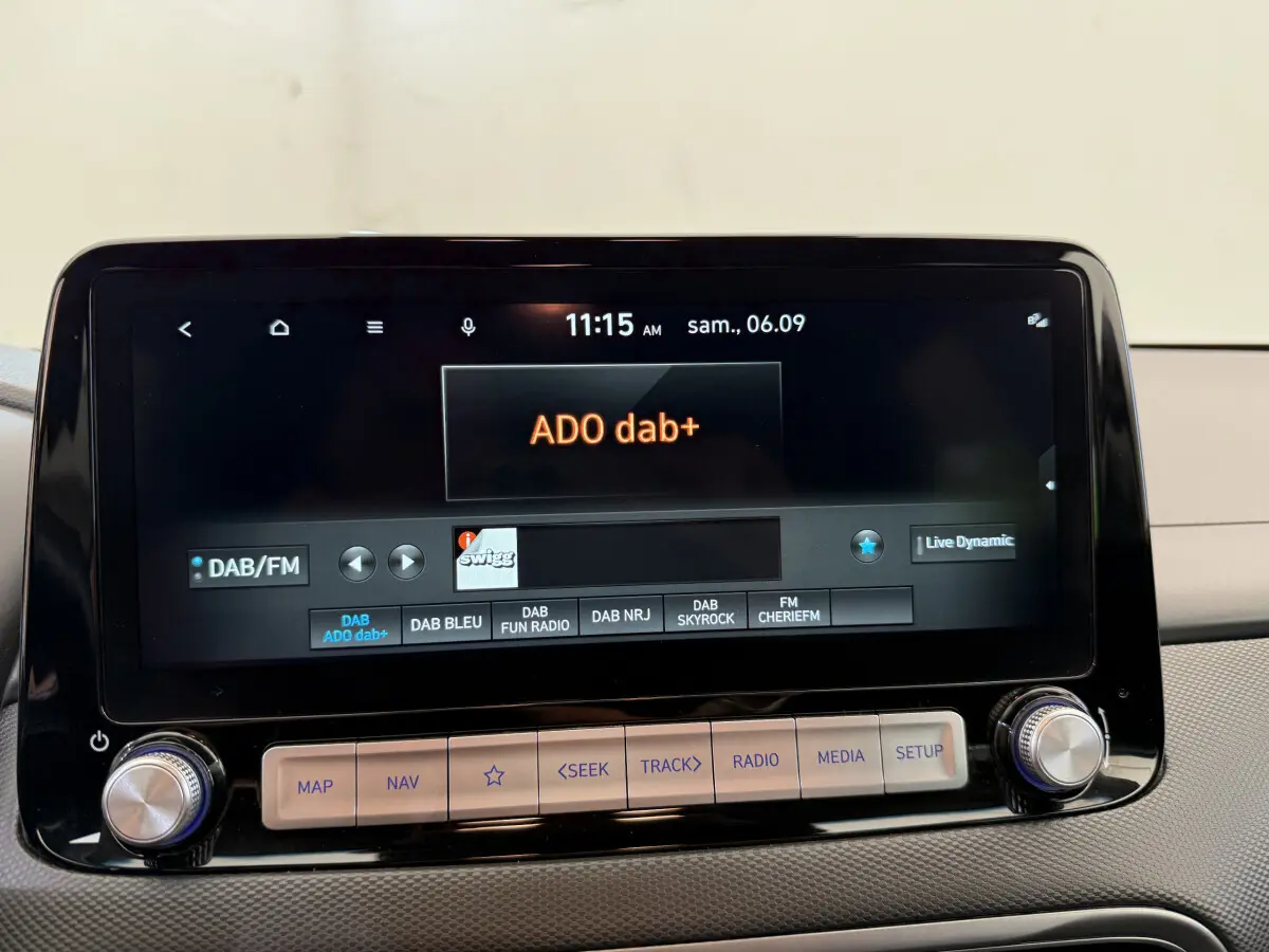 Gros plan sur l'écran tactile central du Hyundai Kona électrique gris clair, affichant la radio DAB+ ADO dab+.