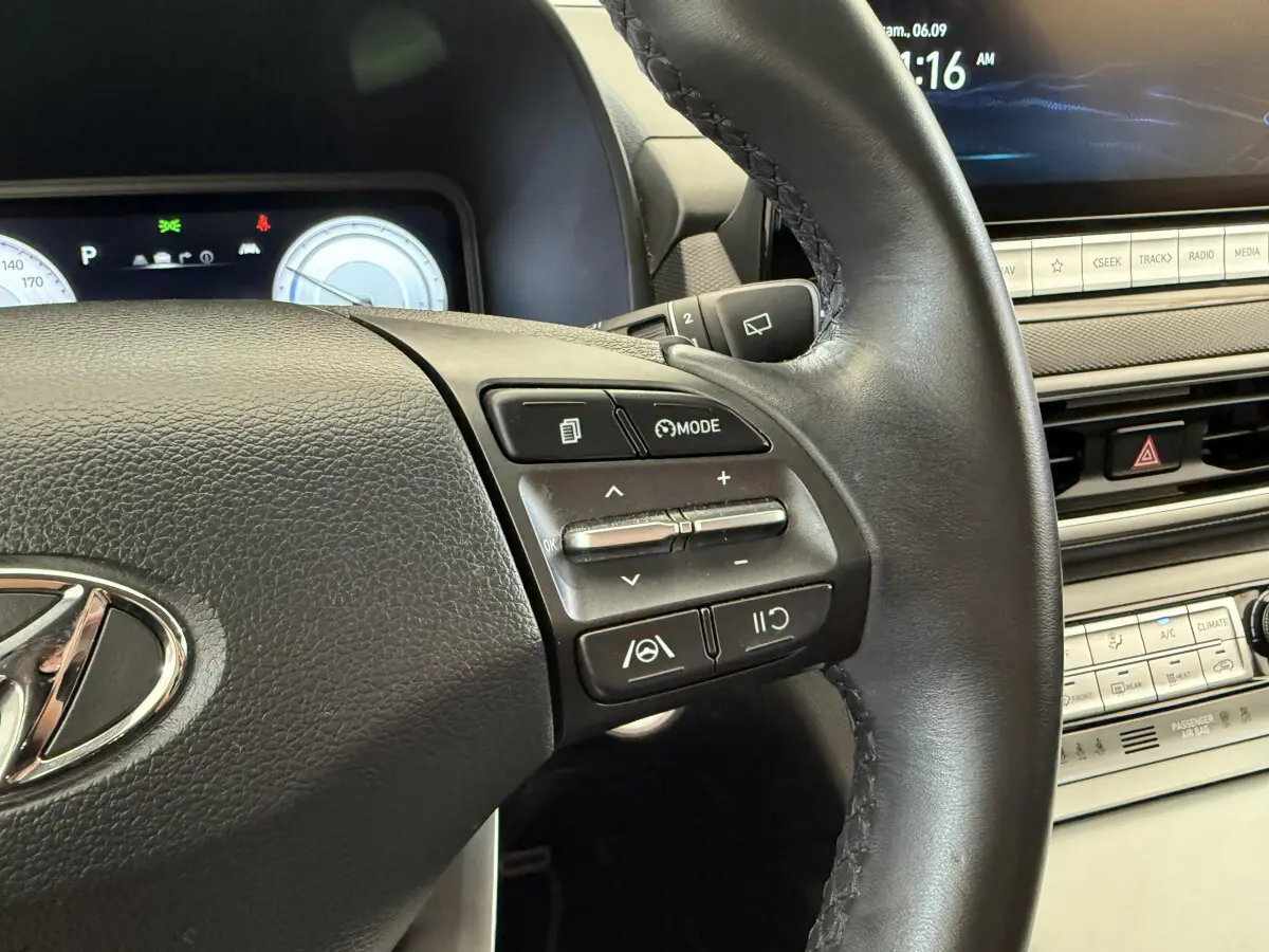 Gros plan sur le volant cuir et les commandes multifonctions du tableau de bord du Hyundai Kona gris clair électrique 2022.