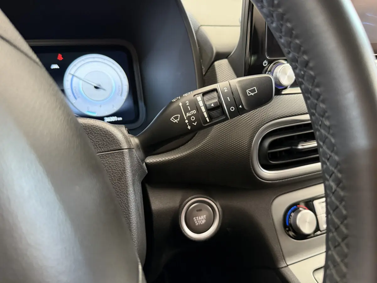 Détail du tableau de bord gris foncé du Hyundai Kona électrique 2022 avec bouton start/stop et commandes d'essuie-glace.