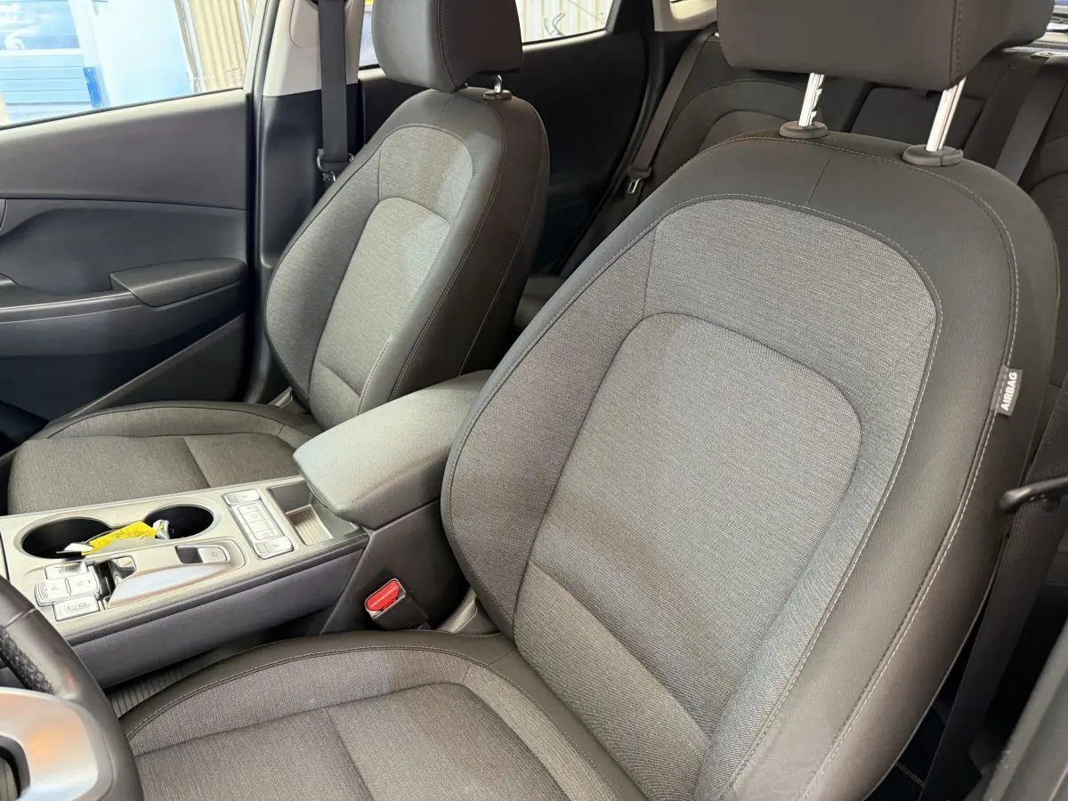 Vue intérieure rapprochée des sièges avant gris clair du Hyundai Kona électrique 2022 avec console centrale et accoudoir.