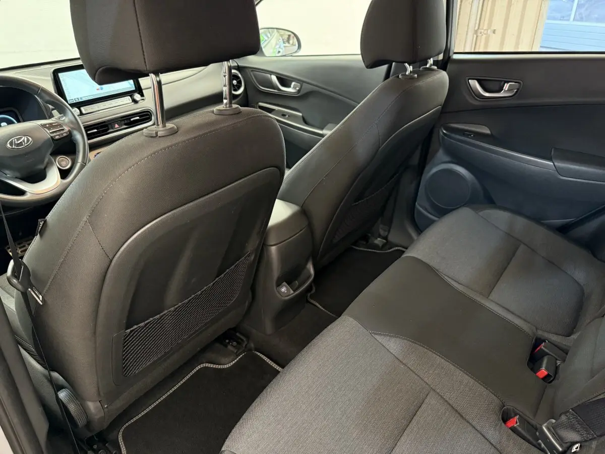 Vue intérieure arrière du Hyundai Kona électrique 2022, sièges tissu gris foncé et console centrale avec port USB.
