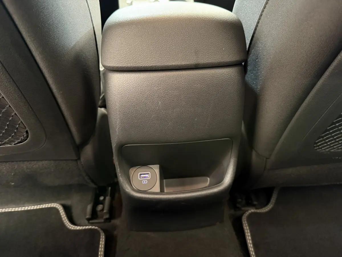 Prise USB arrière et rangement central dans l'habitacle noir du Hyundai Kona électrique gris clair 2022.