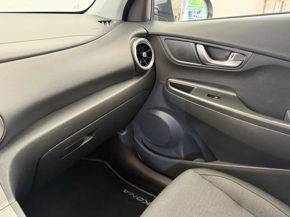Vue intérieure côté passager du tableau de bord et porte de la Hyundai Kona électrique 2022 en gris avec détails noirs.