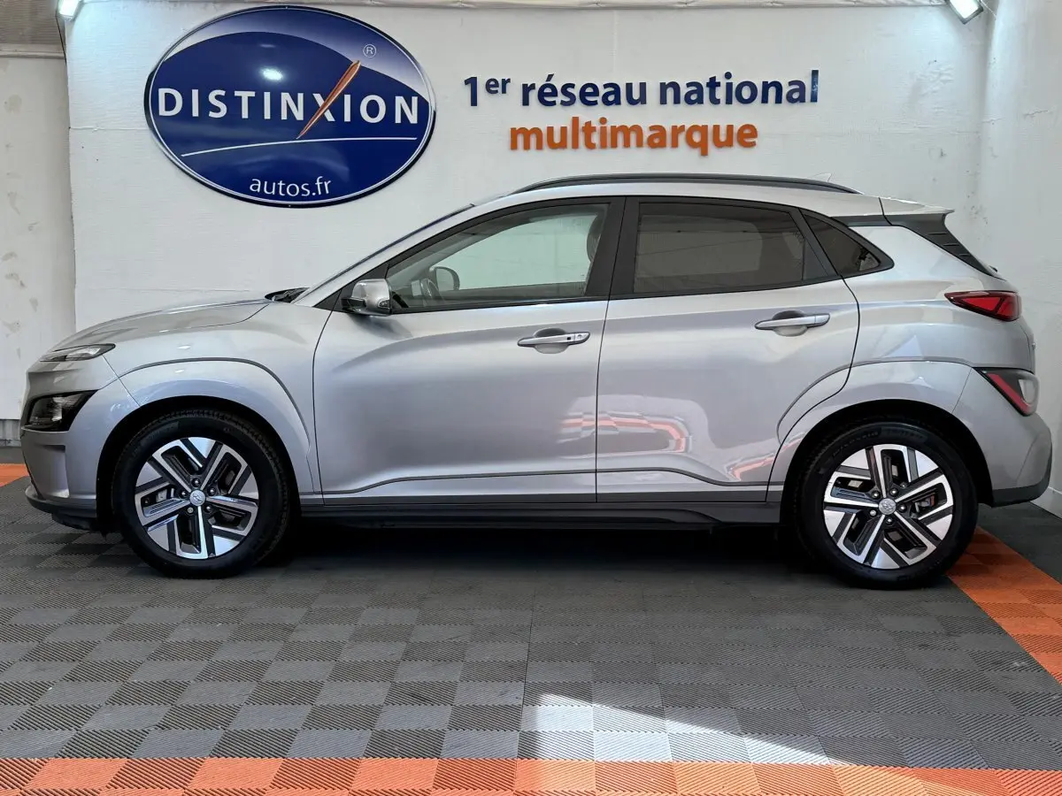 Vue latérale droite d'un Hyundai Kona gris clair électrique 2022, avec jantes modernes et toit noir contrasté.