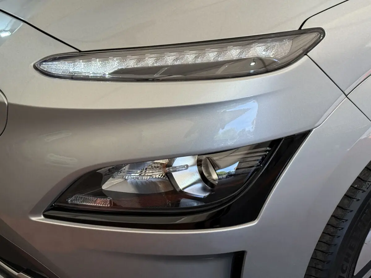Gros plan sur le phare avant droit gris clair du Hyundai Kona électrique 2022 avec feux LED et antibrouillards intégrés.