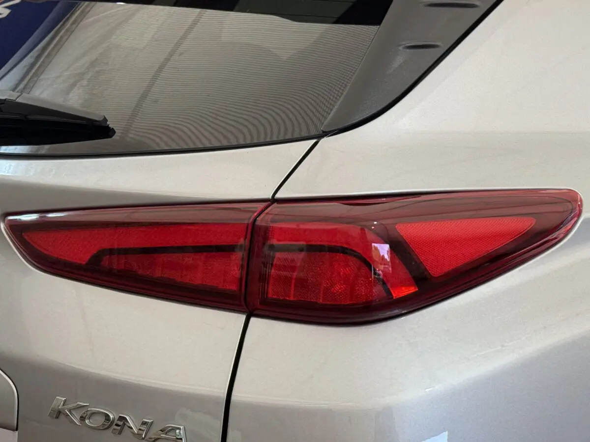 Gros plan sur le feu arrière droit rouge d'un Hyundai Kona gris clair électrique 2022, avec logo visible sur la carrosserie.