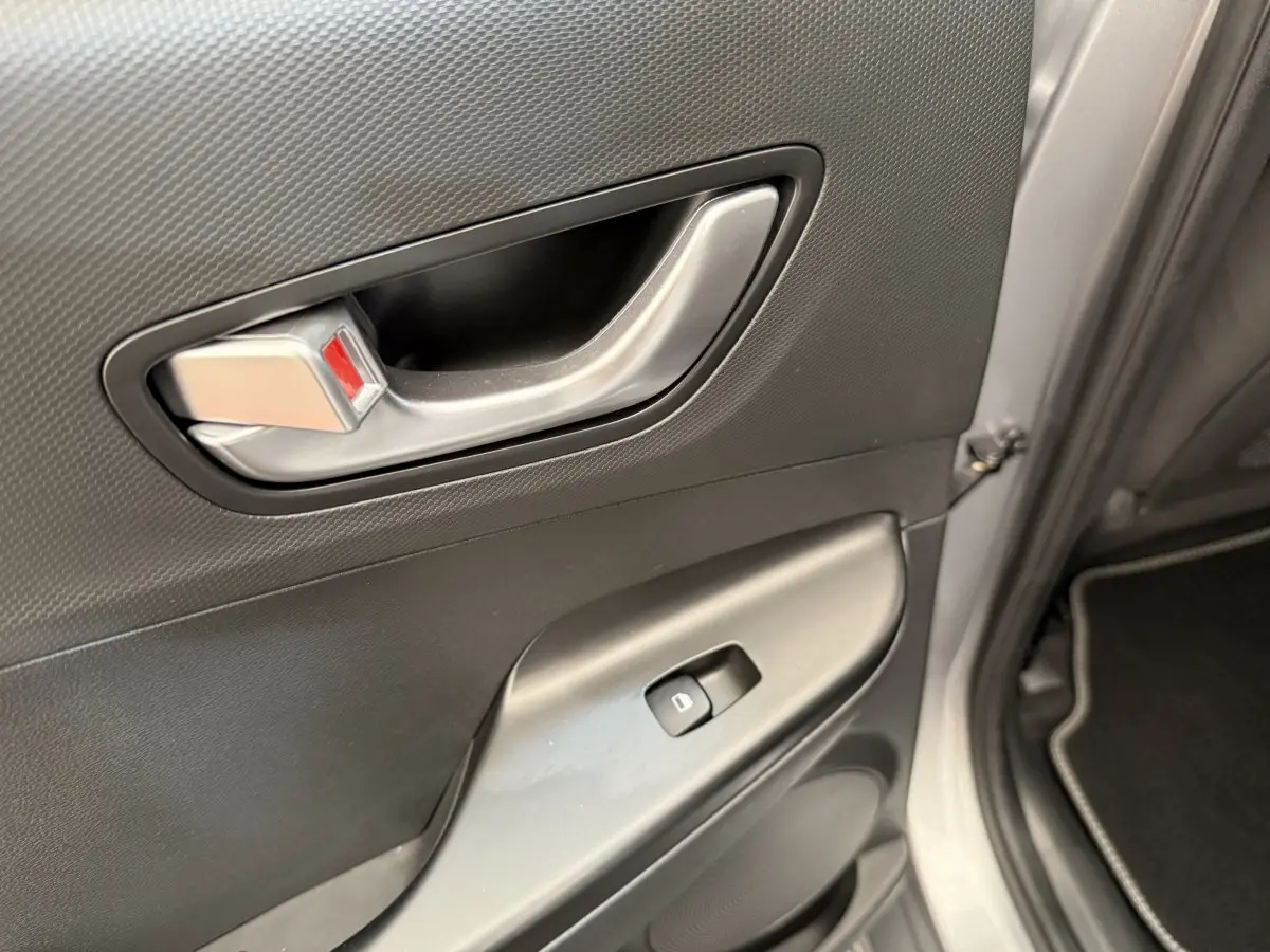 Poignée intérieure et commande de lève-vitre sur la porte avant droite du Hyundai Kona gris clair 2022 électrique.
