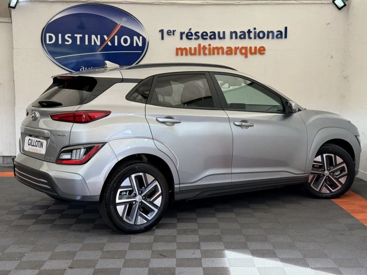 Vue latérale côté droit d'un Hyundai Kona gris clair électrique 2022 avec jantes alliage et toit noir.