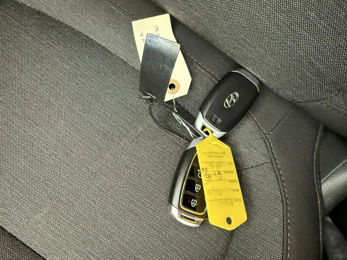 Gros plan sur les clés de contact Hyundai posées sur un siège en tissu gris foncé à l'intérieur du Kona électrique.