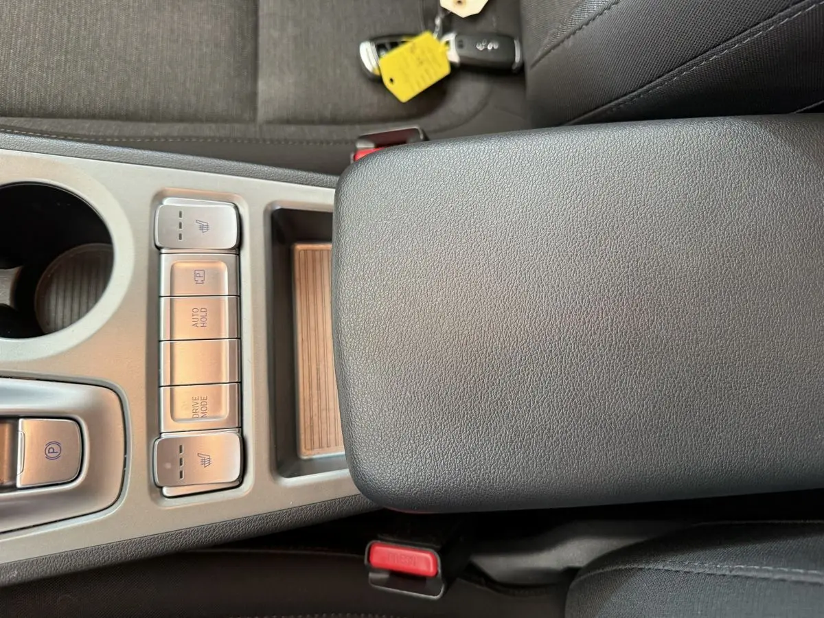 Gros plan sur la console centrale grise du Hyundai Kona électrique 2022, avec boutons chauffants et mode de conduite.