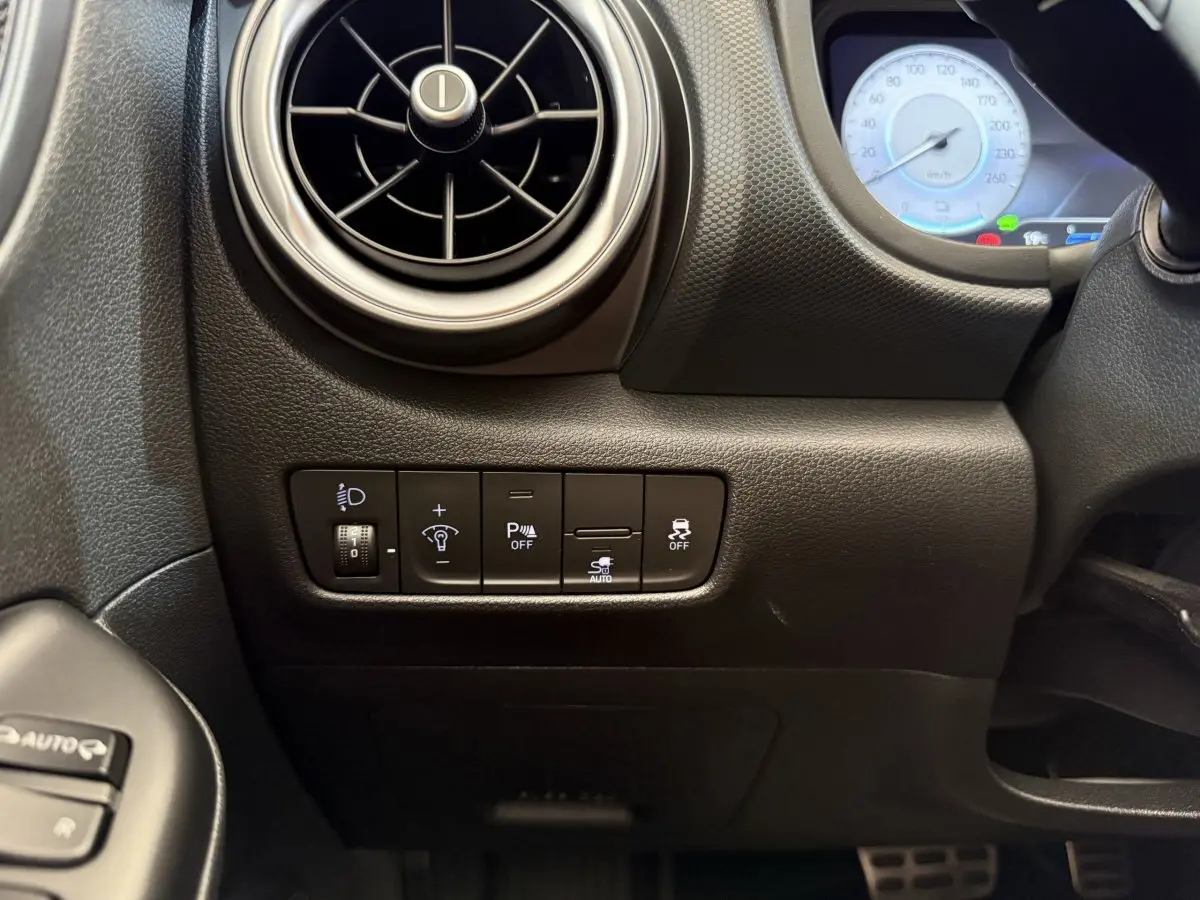 Détail du tableau de bord noir côté gauche du Hyundai Kona électrique 2022 avec commandes d'éclairage et ventilation ronde.