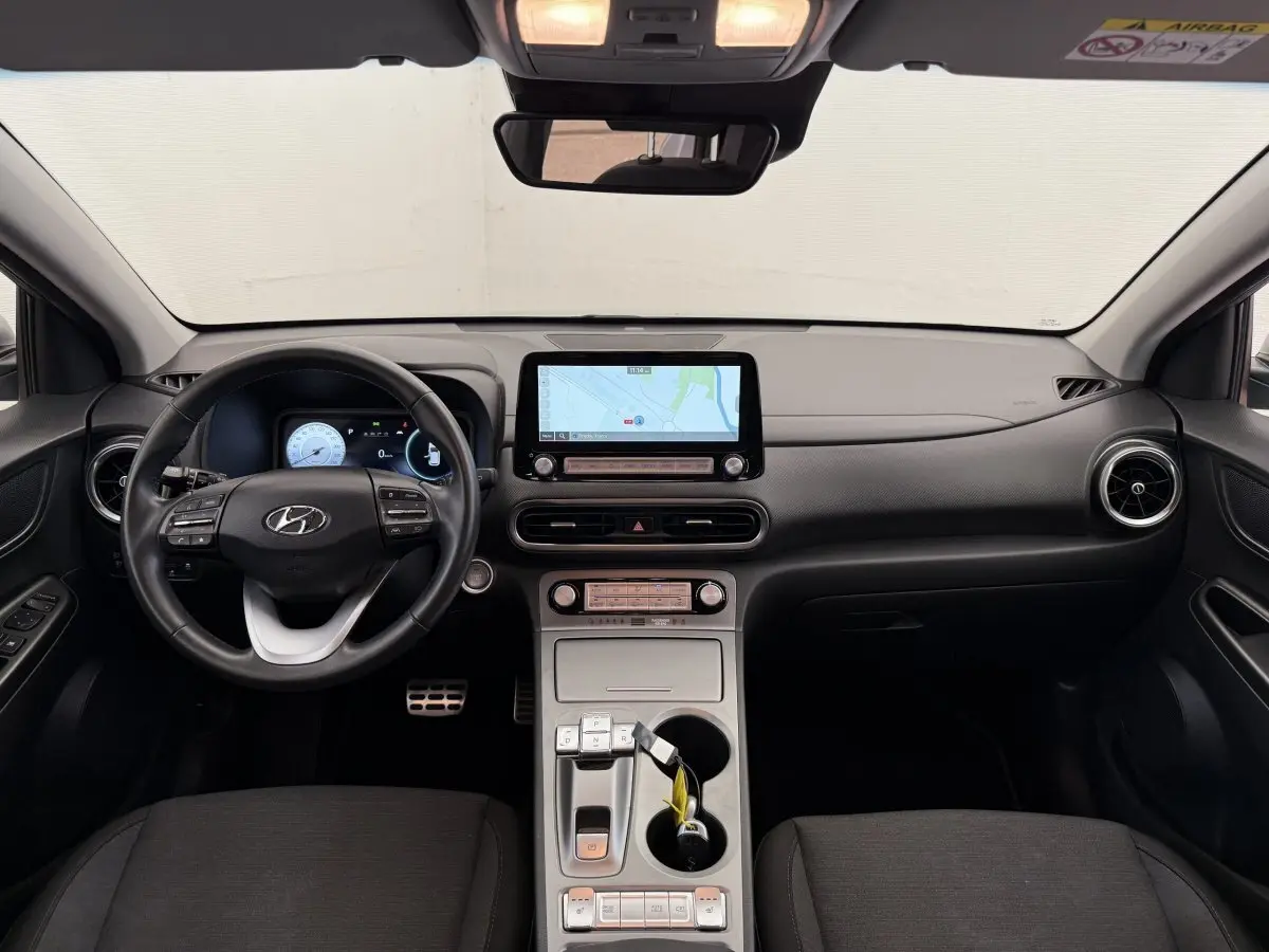 Vue intérieure frontale du tableau de bord du Hyundai Kona électrique 2022 avec écran tactile et volant cuir noir.