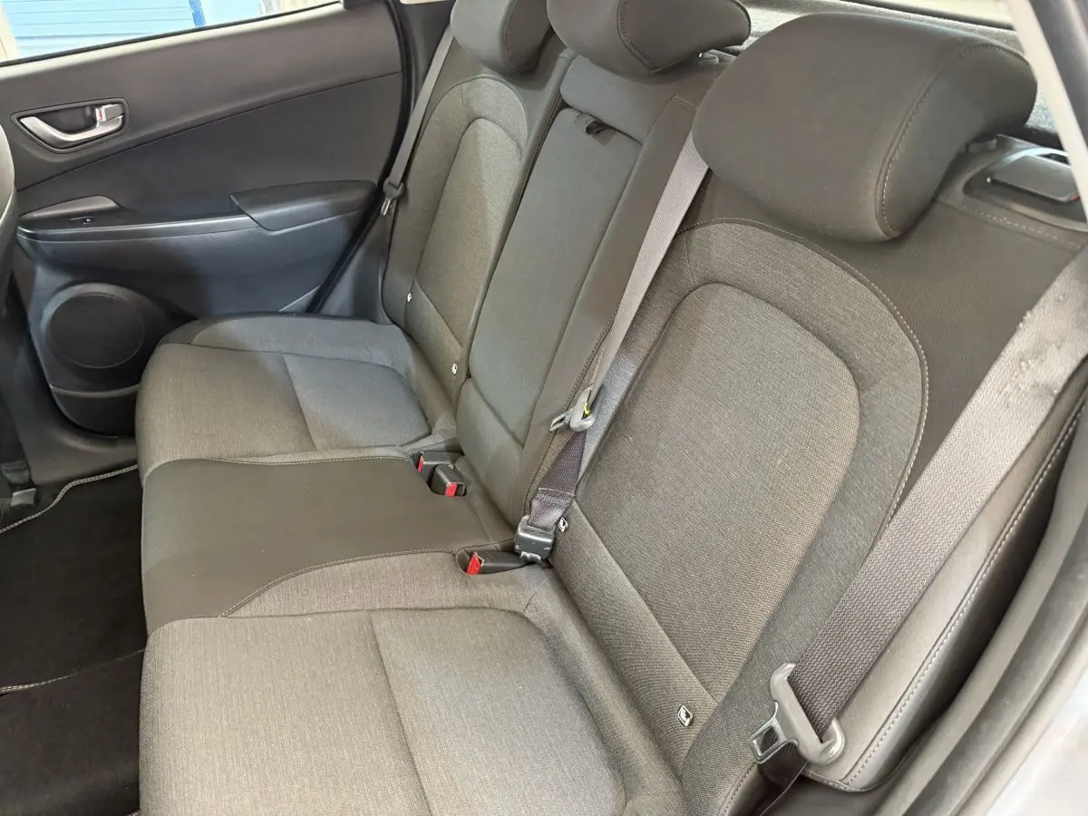 Vue côté droit de la banquette arrière grise en tissu du Hyundai Kona électrique 2022, avec ceinture de sécurité attachée.