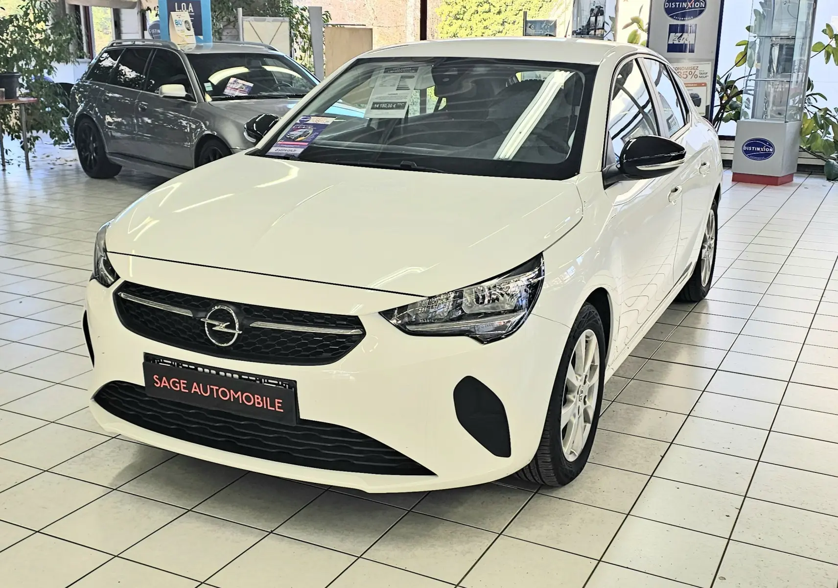 Opel Corsa 1.5D 102ch Edition blanc glacier vue 3/4 avant droit en intérieur, calandre noire et jantes argentées.