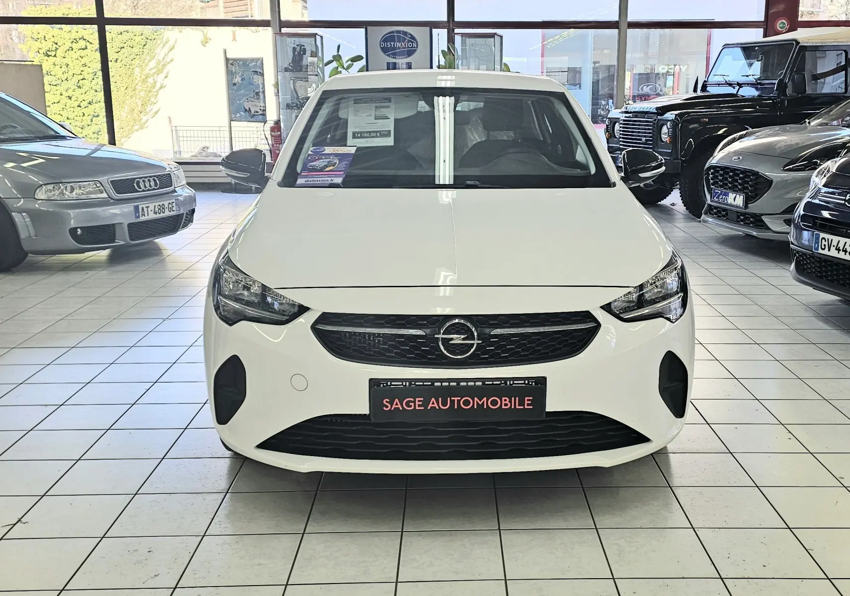 Vue frontale d'une Opel Corsa 1.5D 102ch Edition blanc glacier en showroom avec logo Opel visible sur la calandre.
