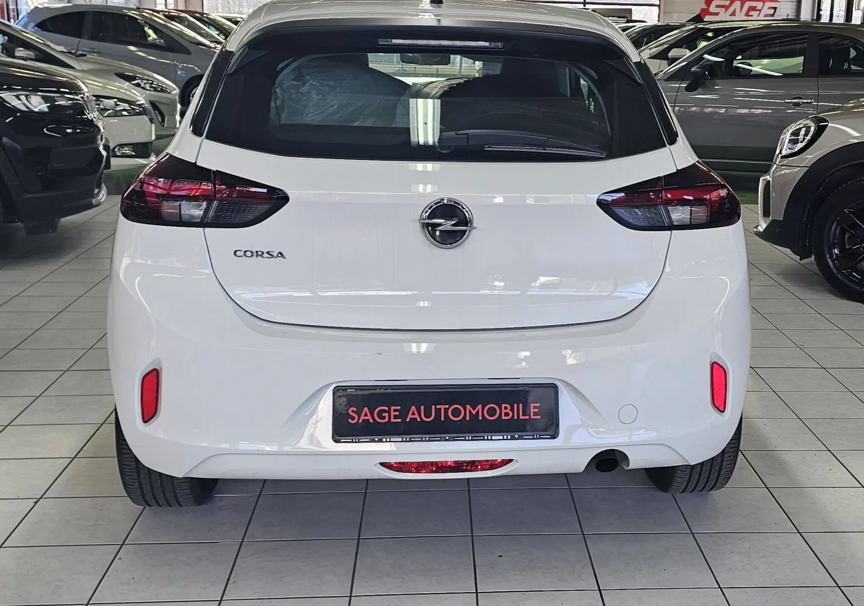 Vue arrière d'une Opel Corsa blanche glacier 5 portes de 2022, avec feux arrière sombres et logo central visible.