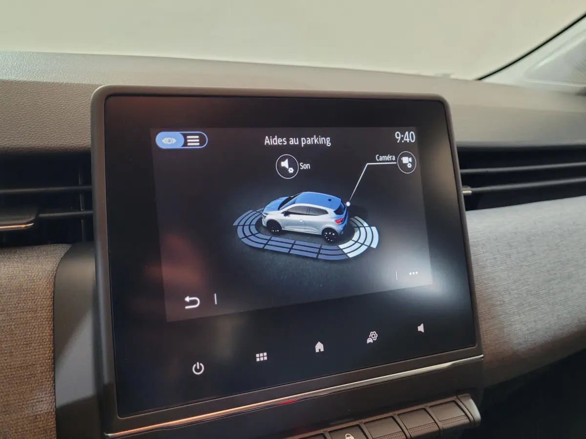 Écran tactile central affichant l'aide au parking avec une Renault Clio bleue vue de dessus en simulation.