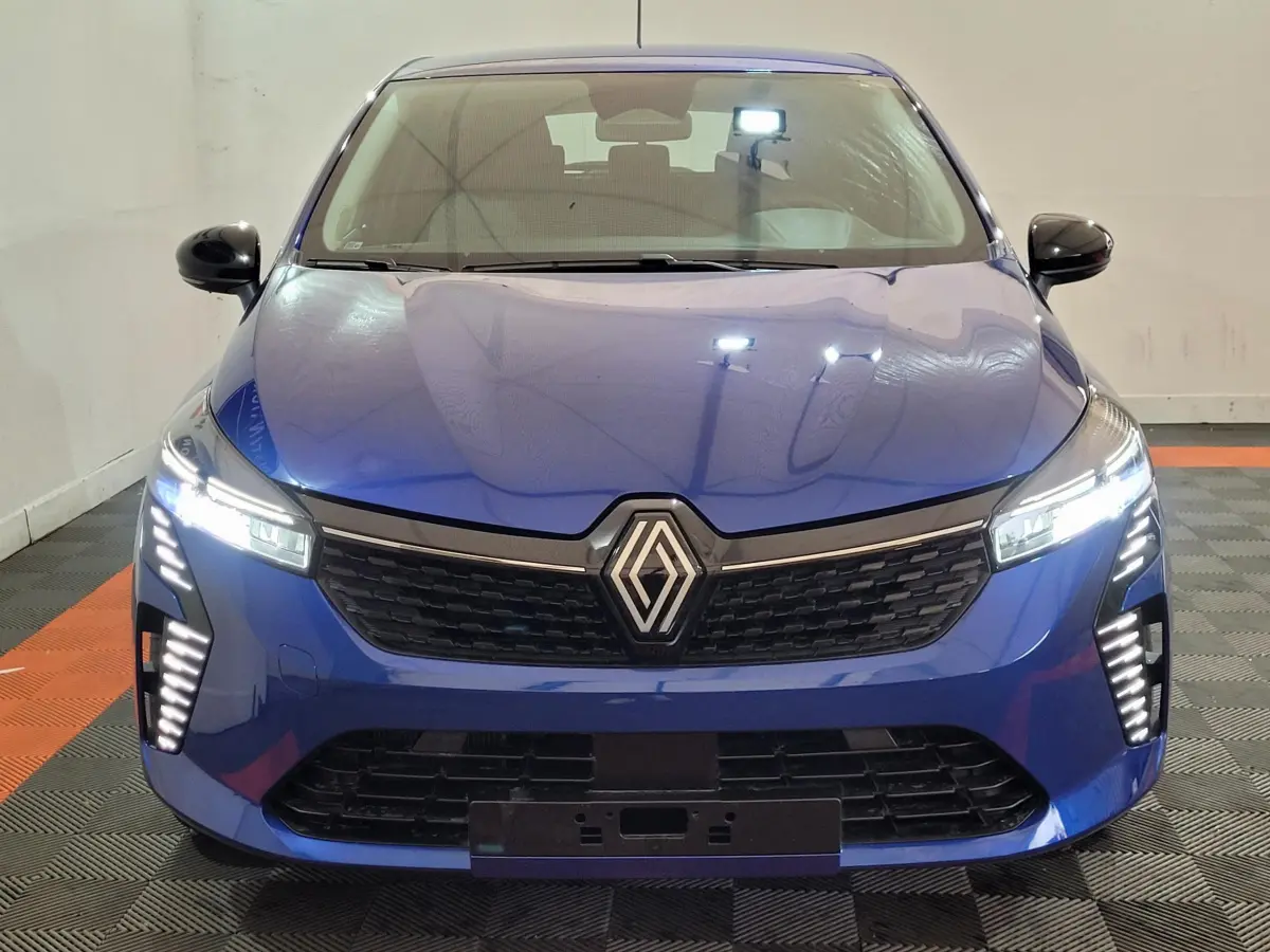Vue frontale d'une Renault Clio Evolution Blue dCi 100 2025 en bleu avec phares LED allumés et calandre noire distinctive.