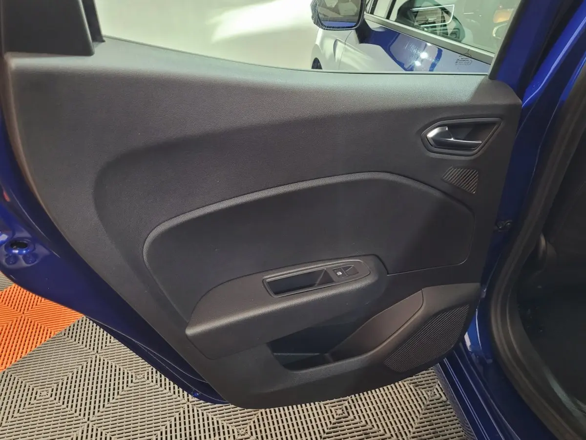 Vue intérieure de la porte arrière gauche d'une Renault Clio bleu 2025 avec commande de fenêtre et haut-parleur intégré.