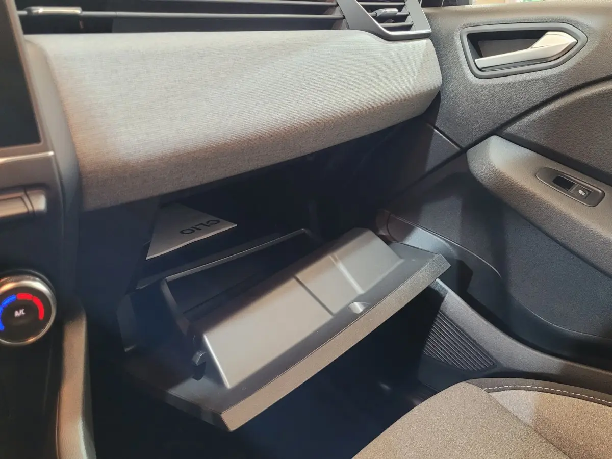 Gros plan de la boîte à gants ouverte côté passager dans l'habitacle gris de la Renault Clio Evolution Blue dCi 100 2025.
