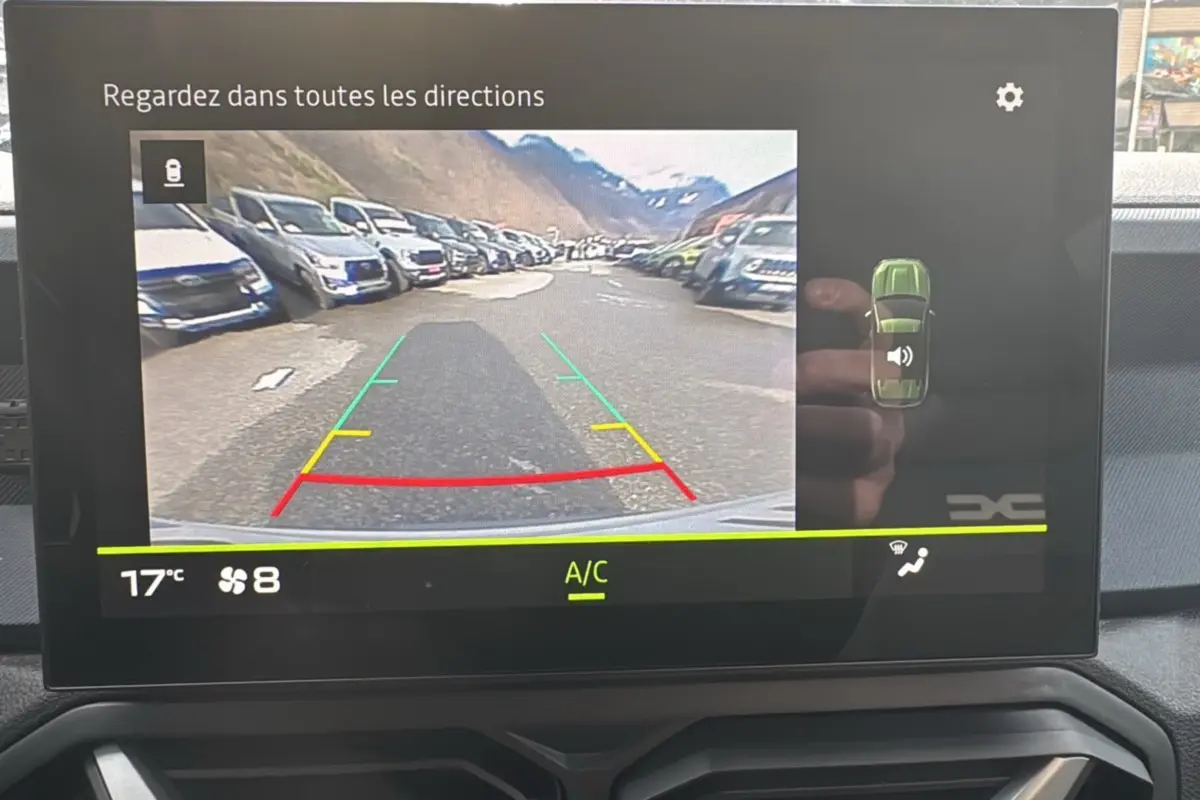 Écran central du Dacia Duster 2025 affichant la caméra de recul avec vue arrière et indications de trajectoire.